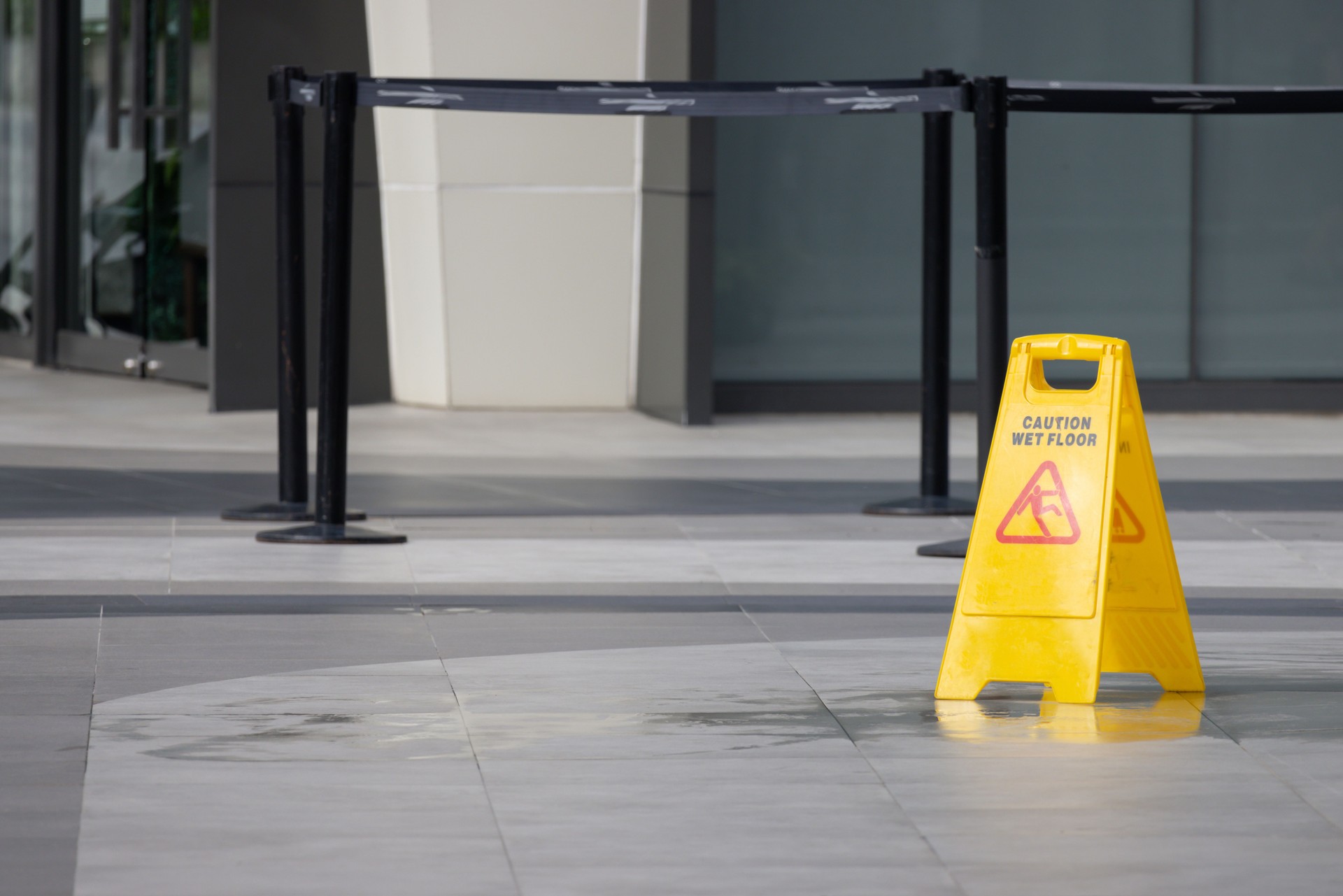 A yellow caution sign is on the ground in front of a building